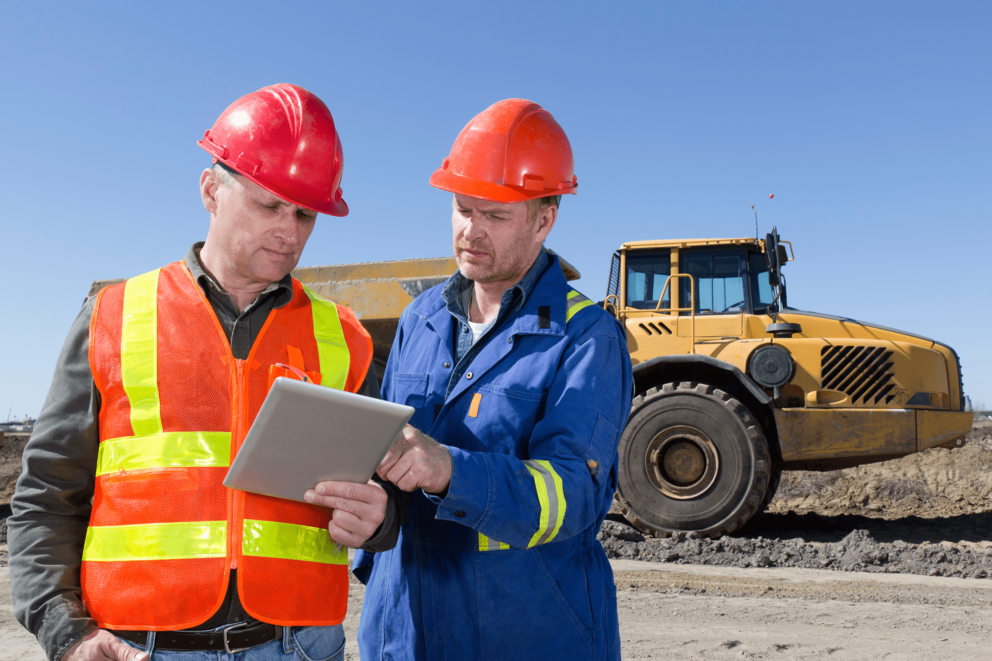 Construction workers reviewing plans on tablet.