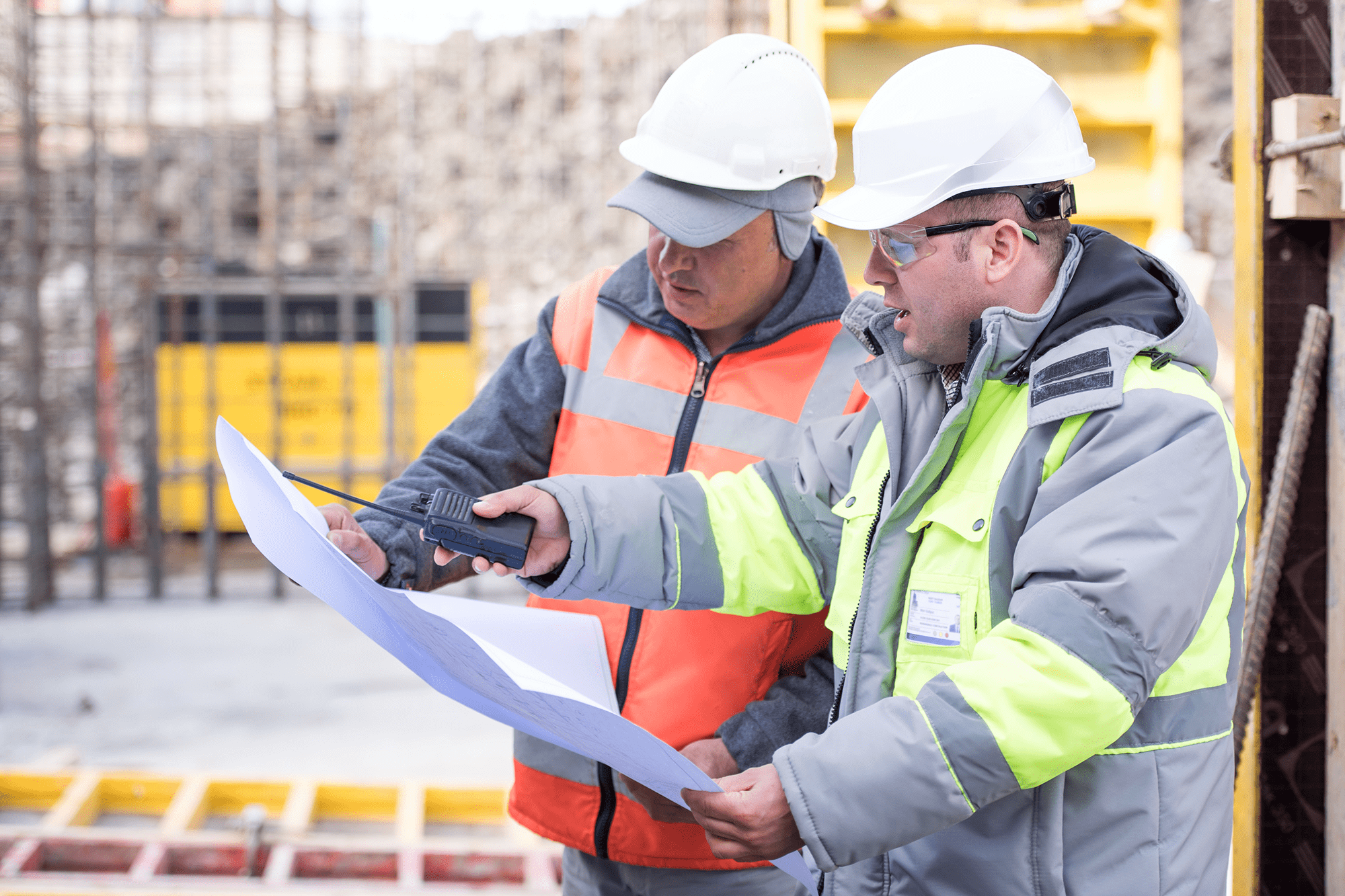 Construction workers reviewing blueprints at site.