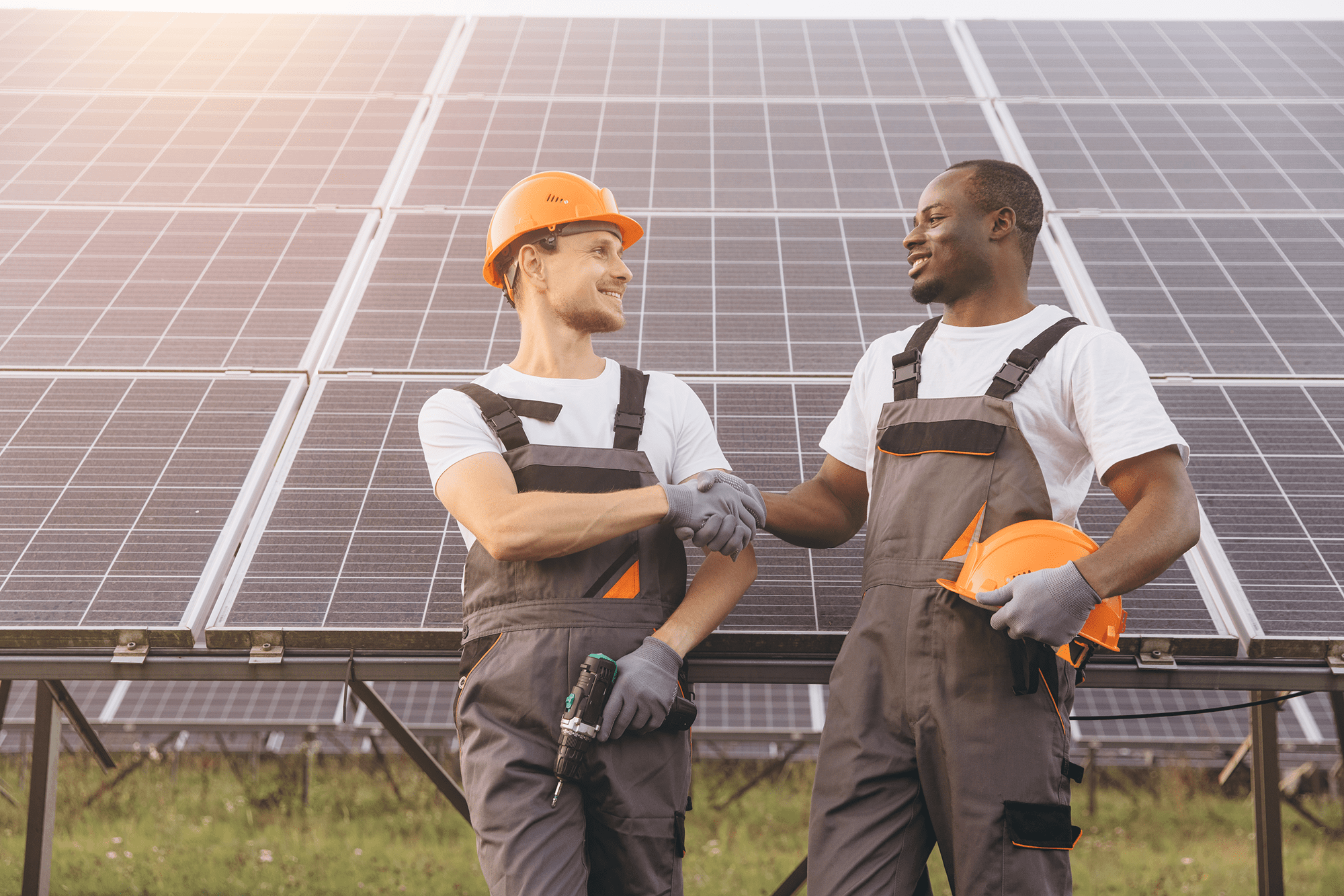 Two workers shaking hands near solar panels.