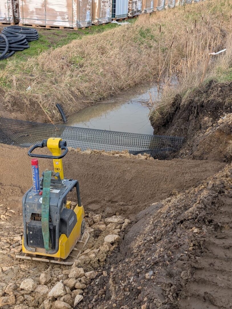 Construction site with soil compactor near water.