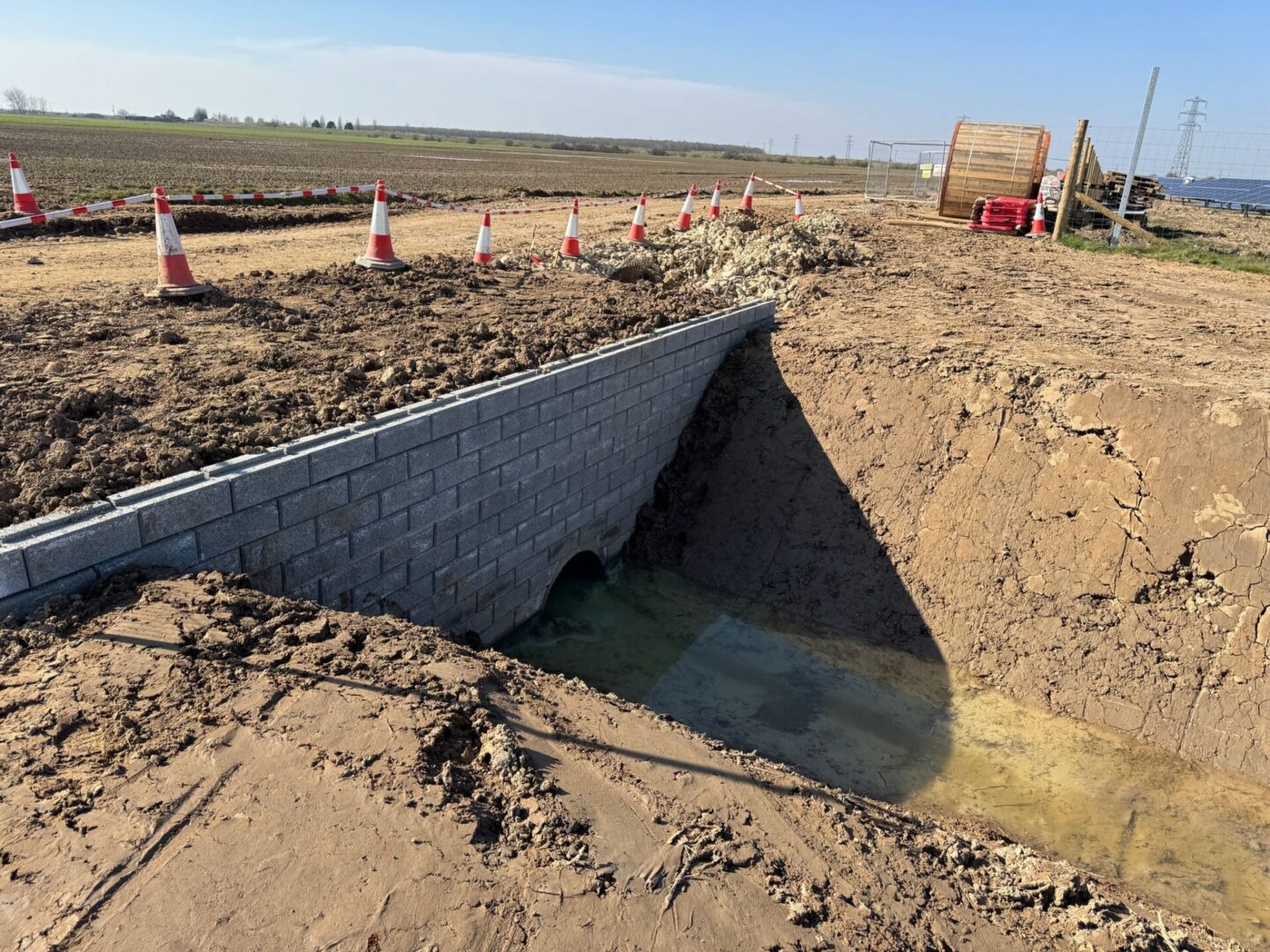 Construction site with drainage ditch and cones.