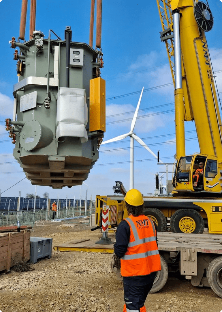 Crane lifting equipment near wind turbine.